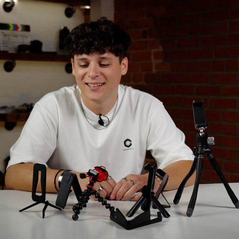Young man wearing white t shirt behind a several mini tripods for smartphones