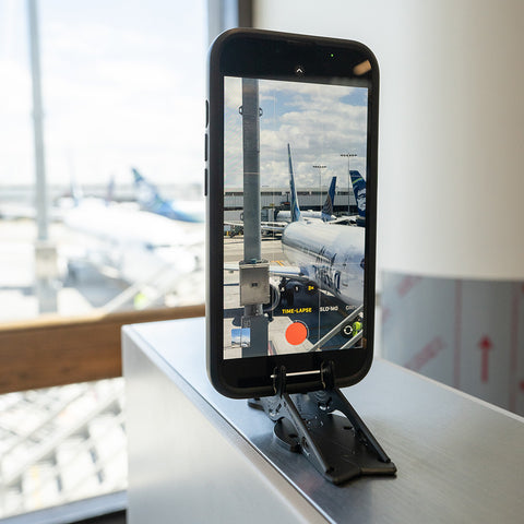 phone stand holding iphone 14 pro filming timelapse of airport