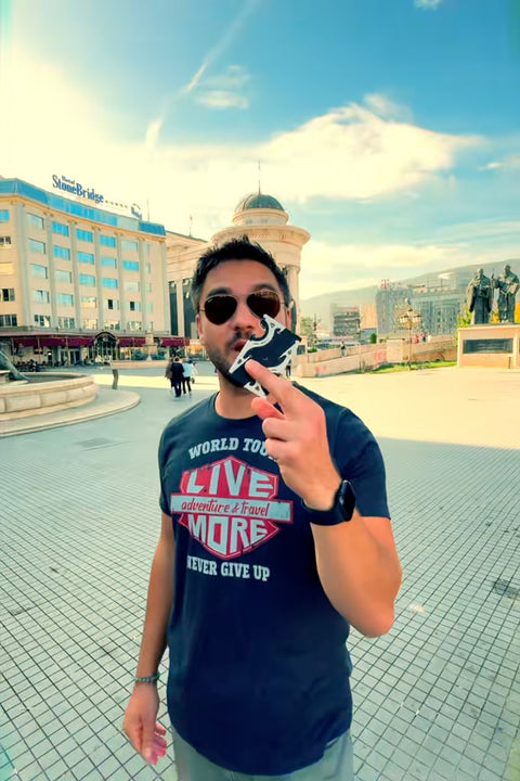 A young man holding up a pocket tripod in card form in a european country