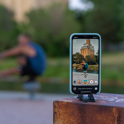An iphone on a tripod stand taking picture of a man doing gym at the background