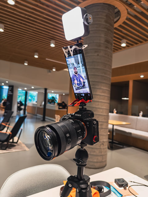 A portable light mounted on a pocket tripod prov2 that is mounted on an android phone that is mounted on a second pocket tripod prov2 that is mounted on a sony camera that is mounted on a tripod in an office setting