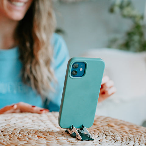 A girl smiling at her phone standing on a tripod to shoot a video