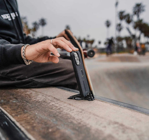 hand of young man in Venice beach skate park, adjusting vertical iphone on Pocket Tripod