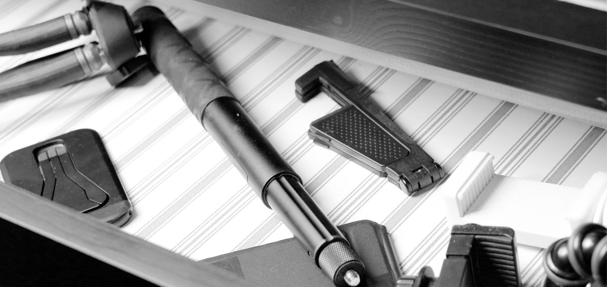 Black-and-white photo: bulky tripods and phone mounts left behind in a drawer