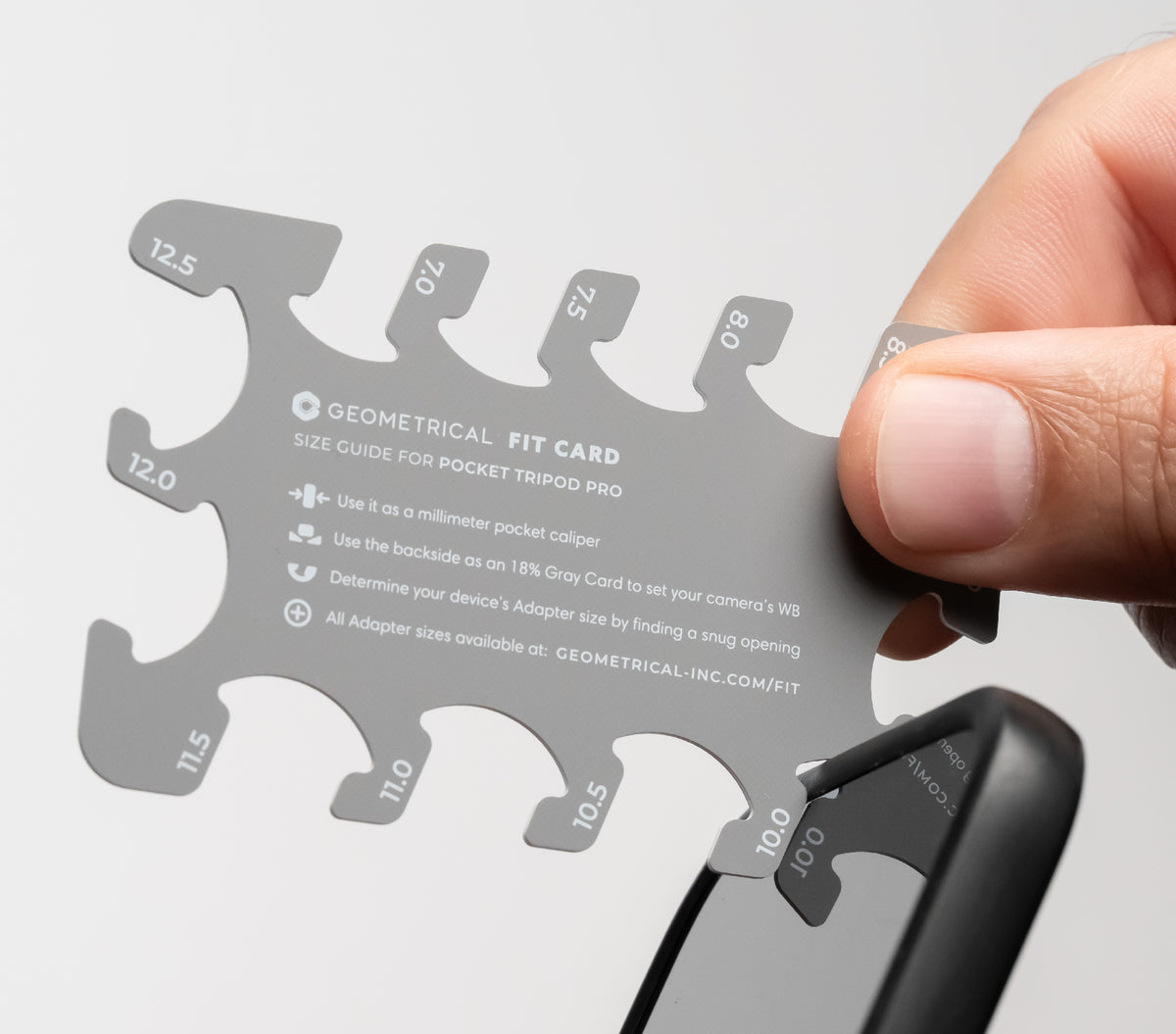 A hand checking a phone's thickness in a slot of the GEOMETRICAL Fit Card