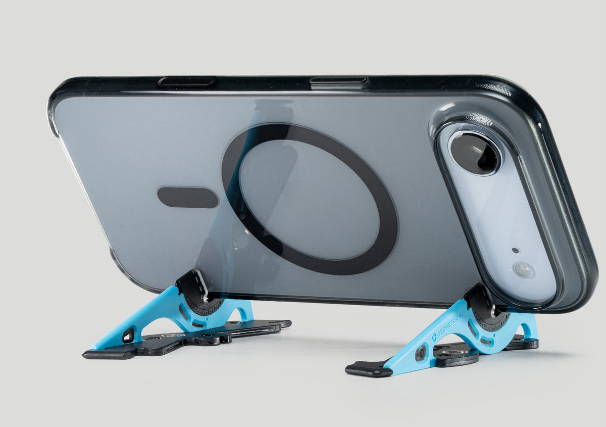 An iPhone in a clear MagSafe case standing in landscape on two blue Pocket Tripod legs
