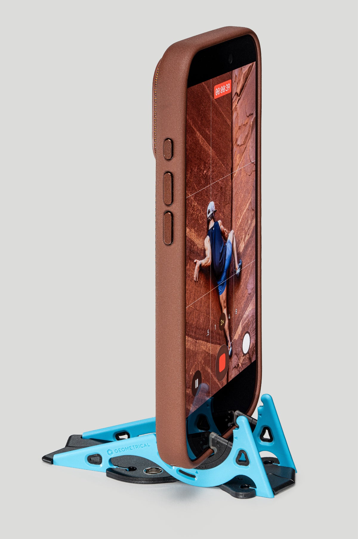A phone in a brown leather case standing upright in a blue Pocket Tripod, recording video