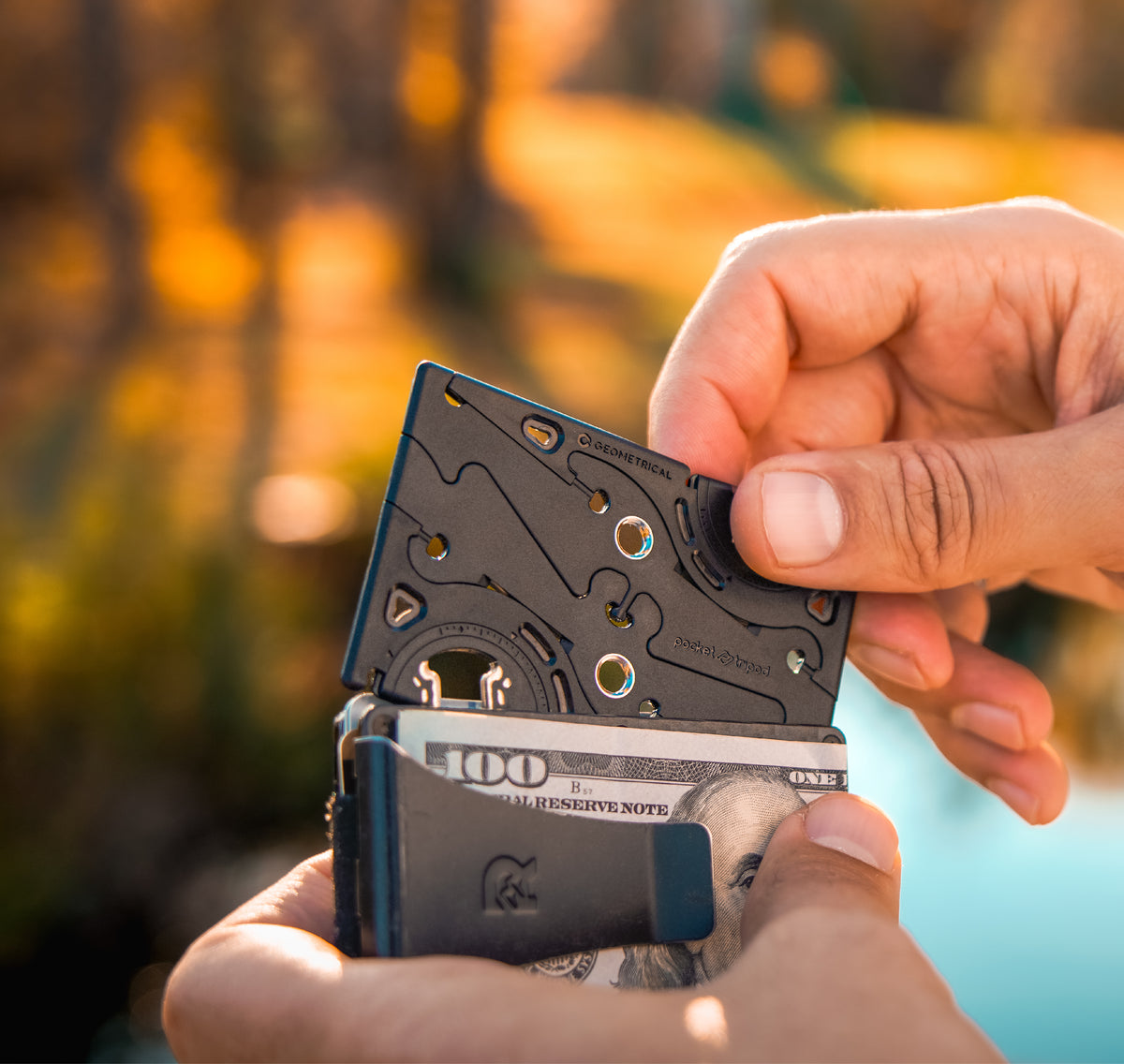 A hand sliding the folded Pocket Tripod PROv2 into a wallet next to banknotes