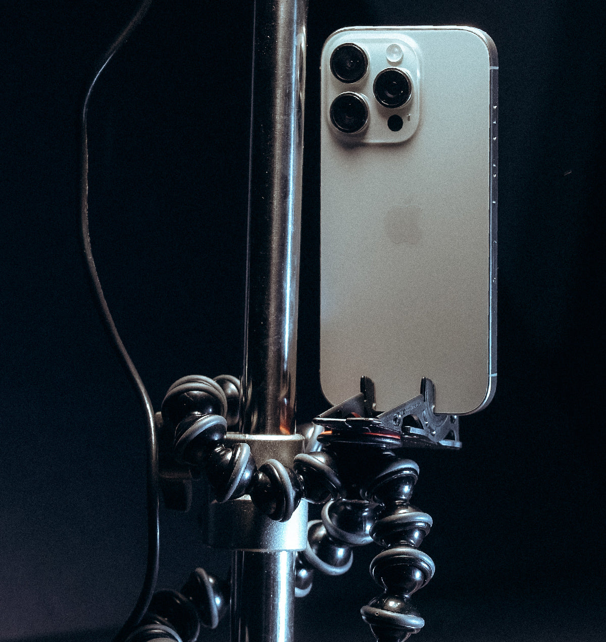 An iPhone held by the Pocket Tripod on a flexible tripod clamped to a pole