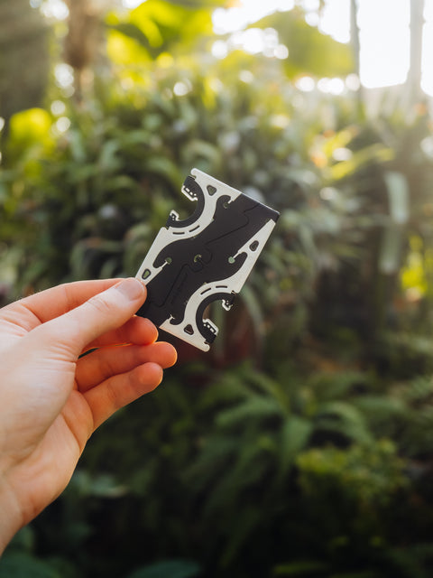 The card sized Pocket Tripod held up in front of greenery and trees