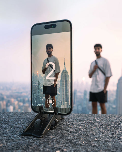 A young man using an iPhone without a case on a Pocket Tripod to take a selfie.