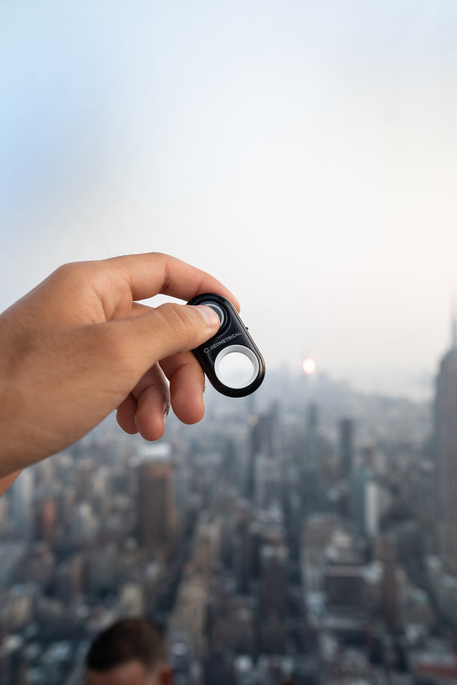 A hand holding the shutter remote high above the Manhattan skyline at dusk