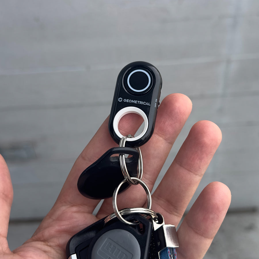 The shutter remote on a keyring alongside house and car keys, held in a palm