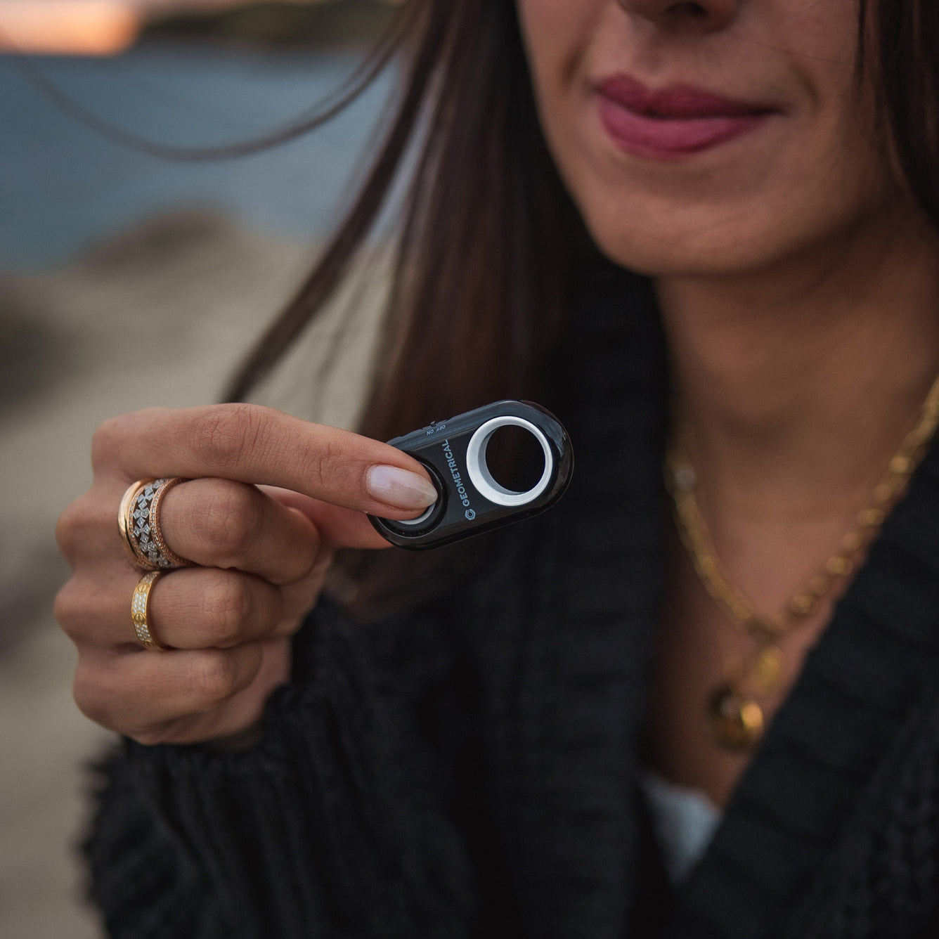 Person holding a small bluetooth remote shutter for phones